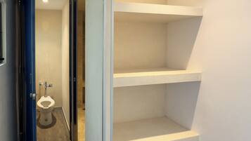 A narrow hallway with a toilet and a shelving unit.