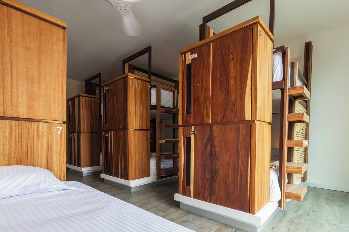 Een kamer met een bed, houten kasten en inbouwplanken.