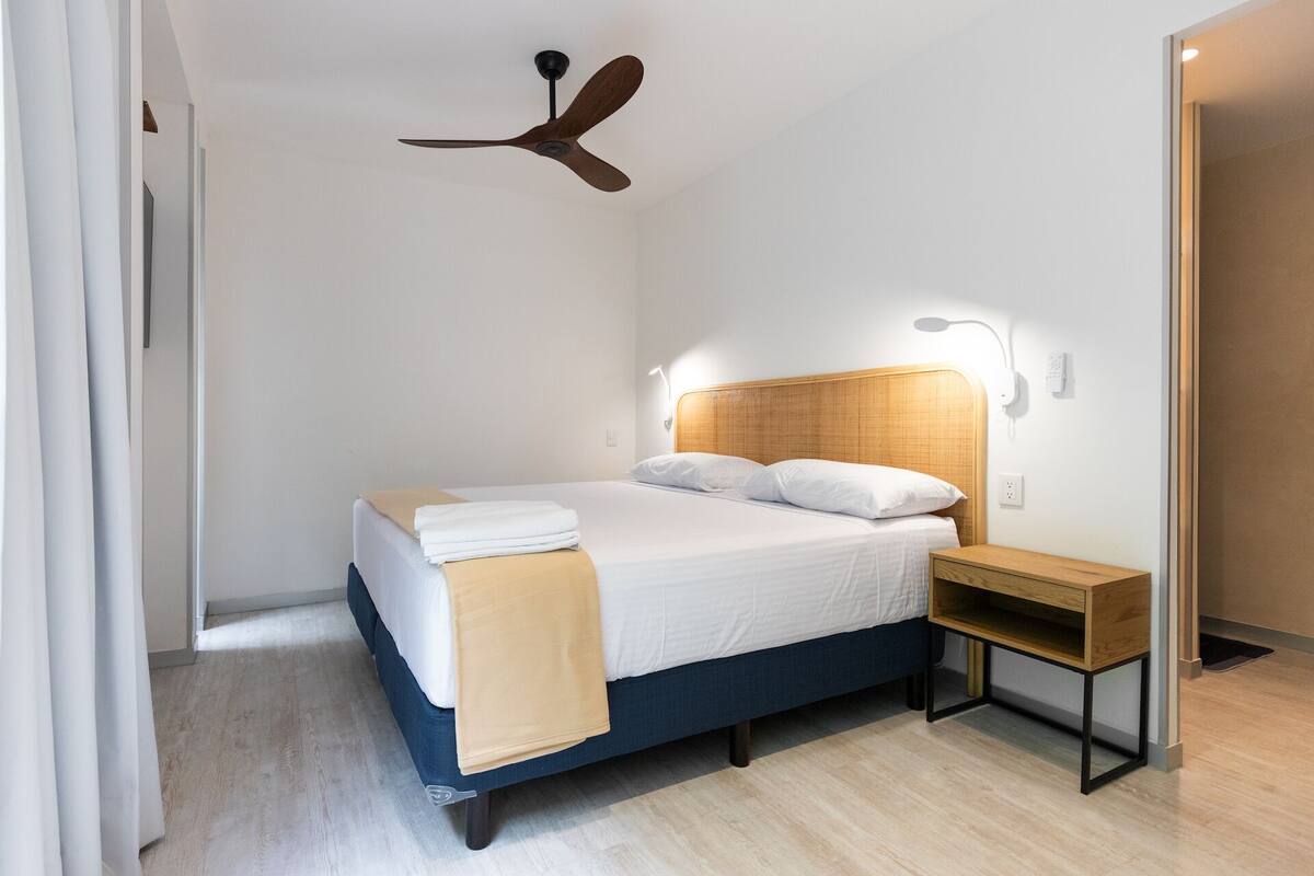 Een moderne slaapkamer met een bed, nachtkastje en een plafondventilator.