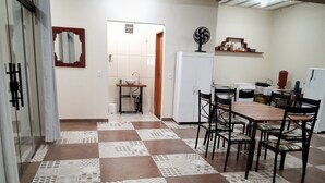 Cuina amb terra de rajola, un rentaplat i un ventilador, i una taula de dinar amb cadires.