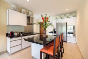 Enjoy cooking in this well-equipped kitchen with a central island, refrigerator, and microwave.