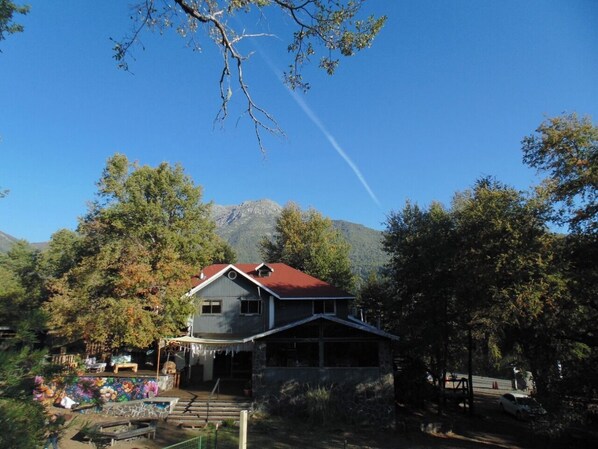 A house with a red roof, surrounded by trees and a mountain in the background. - Hotel Anttuy (Pinto)