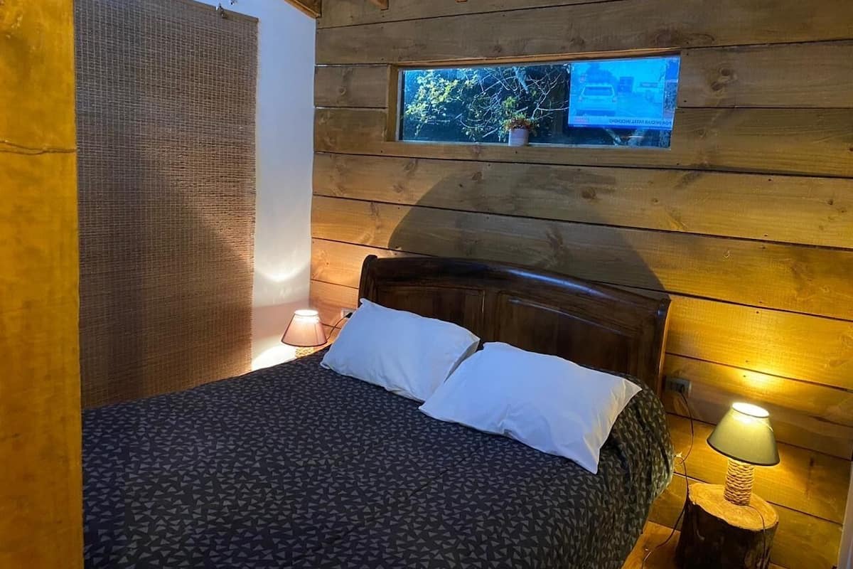 Ein Zimmer mit Holzvertäfelung, einem Bett, zwei Nachttischlampen und einem Fernseher über dem Bett.