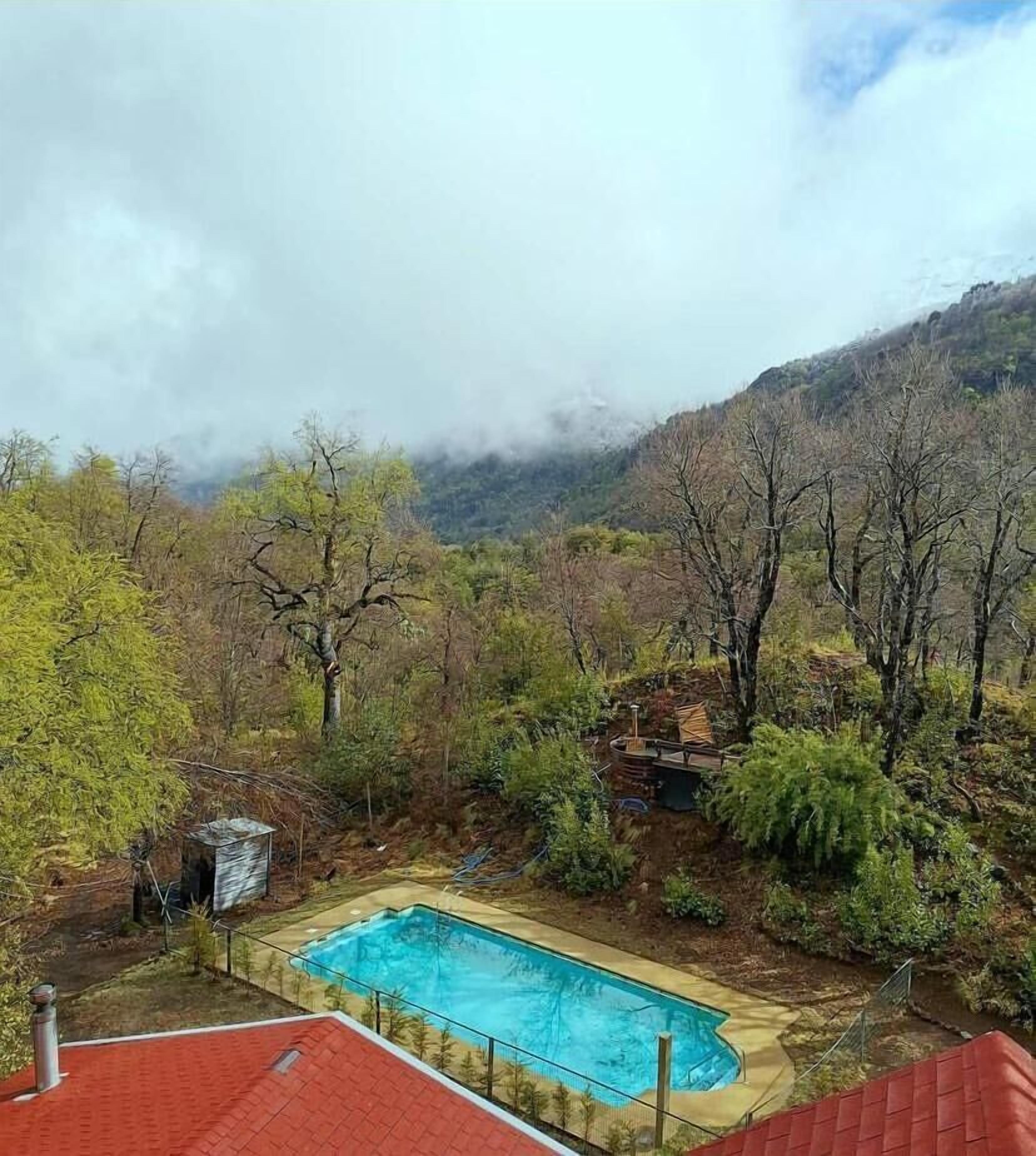 A swimming pool surrounded by trees and mountains.