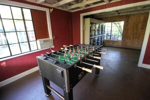 A foosball table in a room with red walls and large windows.