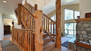 Una escalera de madera con diseño rústico que conduce a una chimenea de piedra y vistas al exterior.