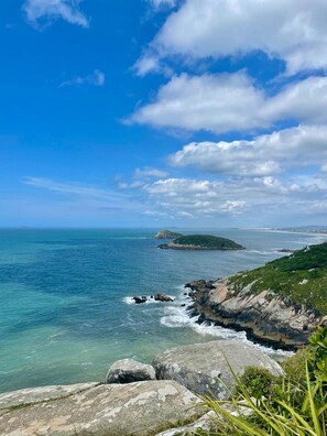 A coastal landscape with clear skies, rocky terrain, and a view of the ocean. - Refúgio Farol Ponta do Catalão - SC (Imbituba)
