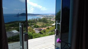 Une vue depuis un balcon donnant sur une zone côtière, avec un pont, de la végétation et des bâtiments.