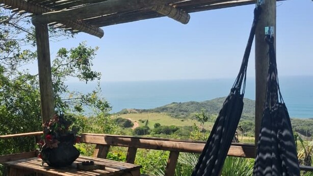 Une terrasse en bois avec un hamac, une table de pique-nique et des plantes en pot.