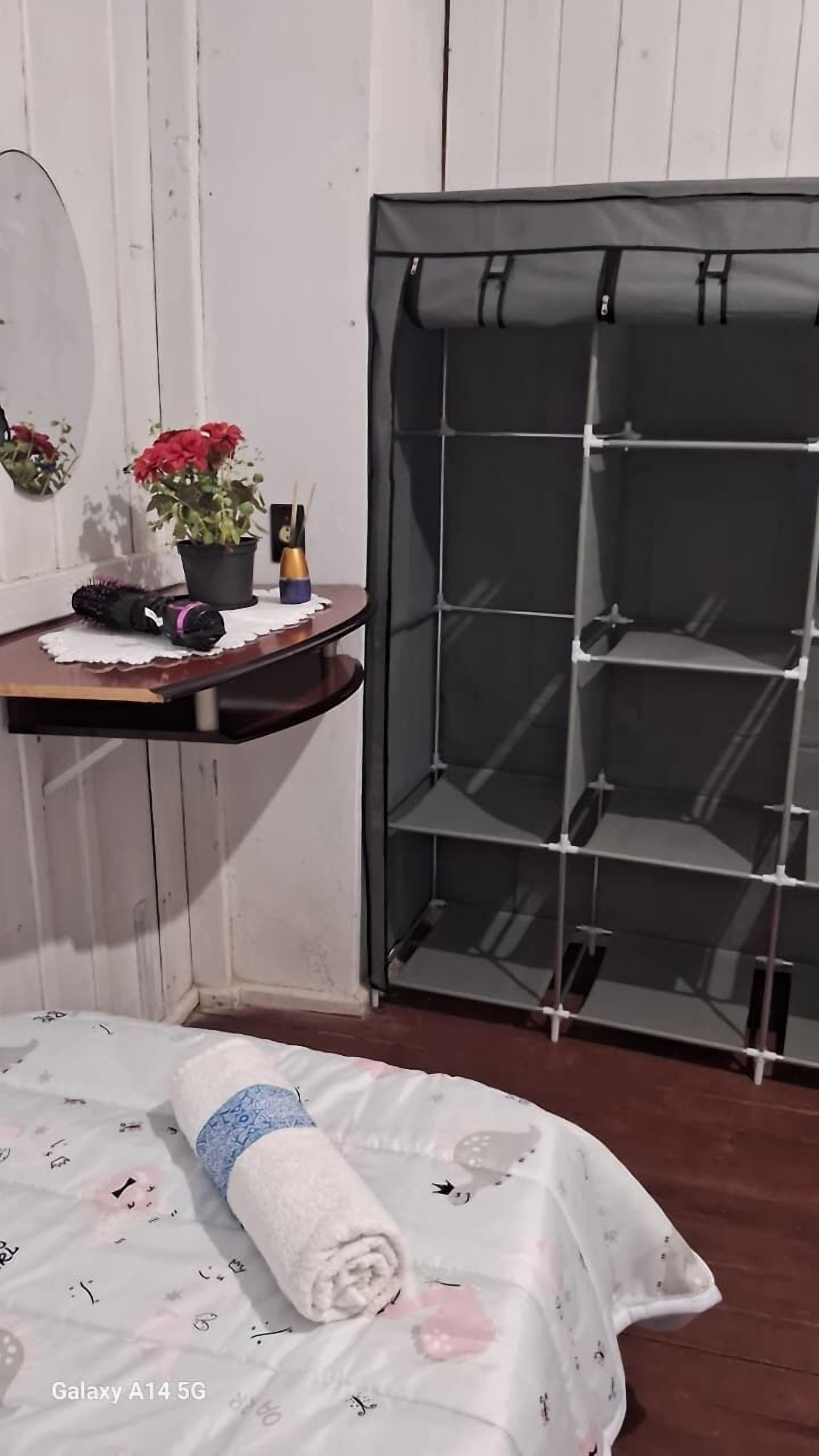 Una camera da letto con un letto, un comodino con una pianta e un'unità di contenimento.