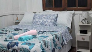 A bedroom with a bed, a nightstand, a window, and a ceiling with exposed beams. - Refúgio Farol Ponta do Catalão - SC (Imbituba)