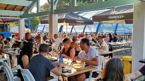 An outdoor dining area with tables and chairs under a covered roof. - ZEcamping 4* piscine couverte toboggans locatif 36m2 6 pers (Névez)