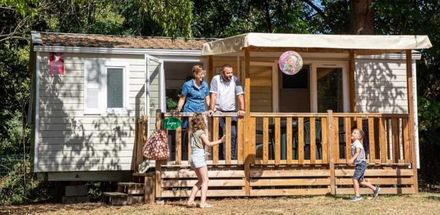 Een stacaravan met een houten terras en een overdekte veranda.