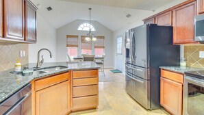 A kitchen with wooden cabinets, a stainless steel refrigerator, and a granite countertop. - 3 Mi to Oglethorpe Mall: Home w/ Fenced Yard! (Savannah)