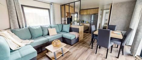 A modern living room with a sofa, a coffee table, and a dining area with chairs and a table.