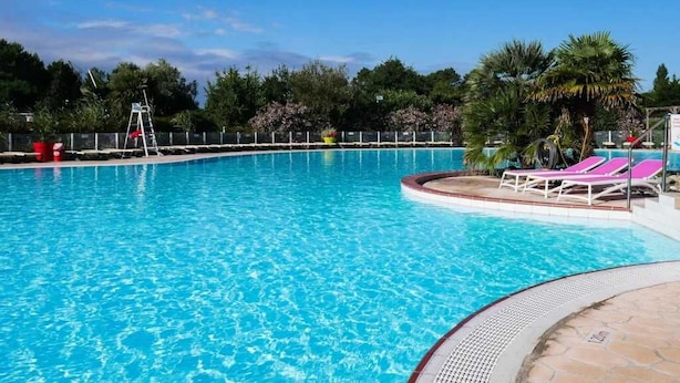 A clear blue swimming pool with lounge chairs and a ladder.