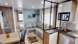 A compact living space with a kitchenette, a dining area, and a seating area with a sofa and chairs.