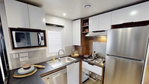 A compact kitchen with a microwave, sink, stove, and refrigerator.