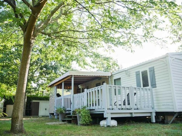 A mobile home with a porch and a fenced deck.