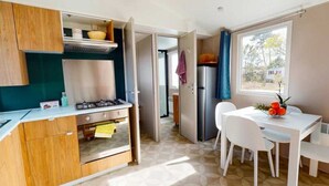 A compact kitchen with a gas stove, a refrigerator, and a dining area with a table and chairs.