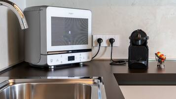 A kitchen with a built-in microwave, a coffee maker, and a stainless steel sink.