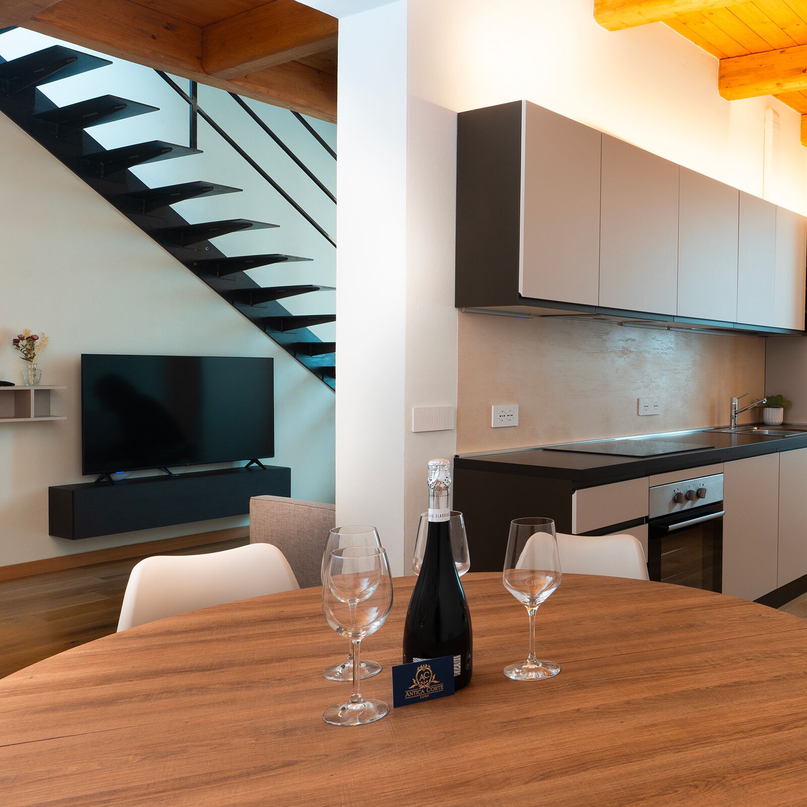 Een moderne keuken met een eethoek, een televisie en een fles wijn op tafel.
