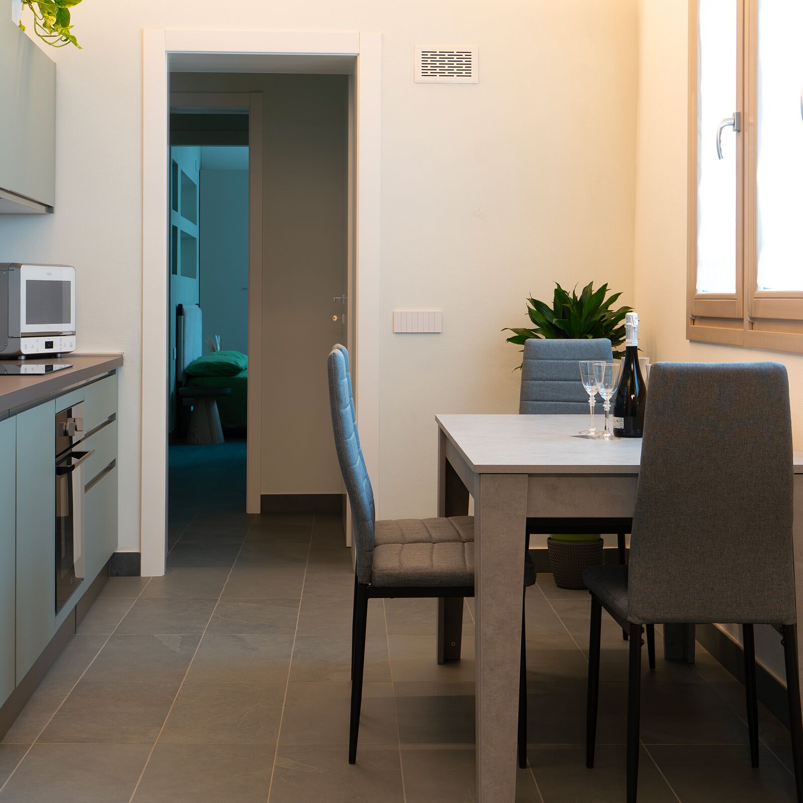 A modern kitchen with a dining area, a television, and a potted plant.