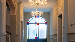 A hallway with a chandelier, a stained glass window, and a staircase. - Antica Corte Lugo (Lugo)