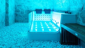 A stone-walled spa area with a hot tub and a wooden bench. - Antica Corte Lugo (Lugo)