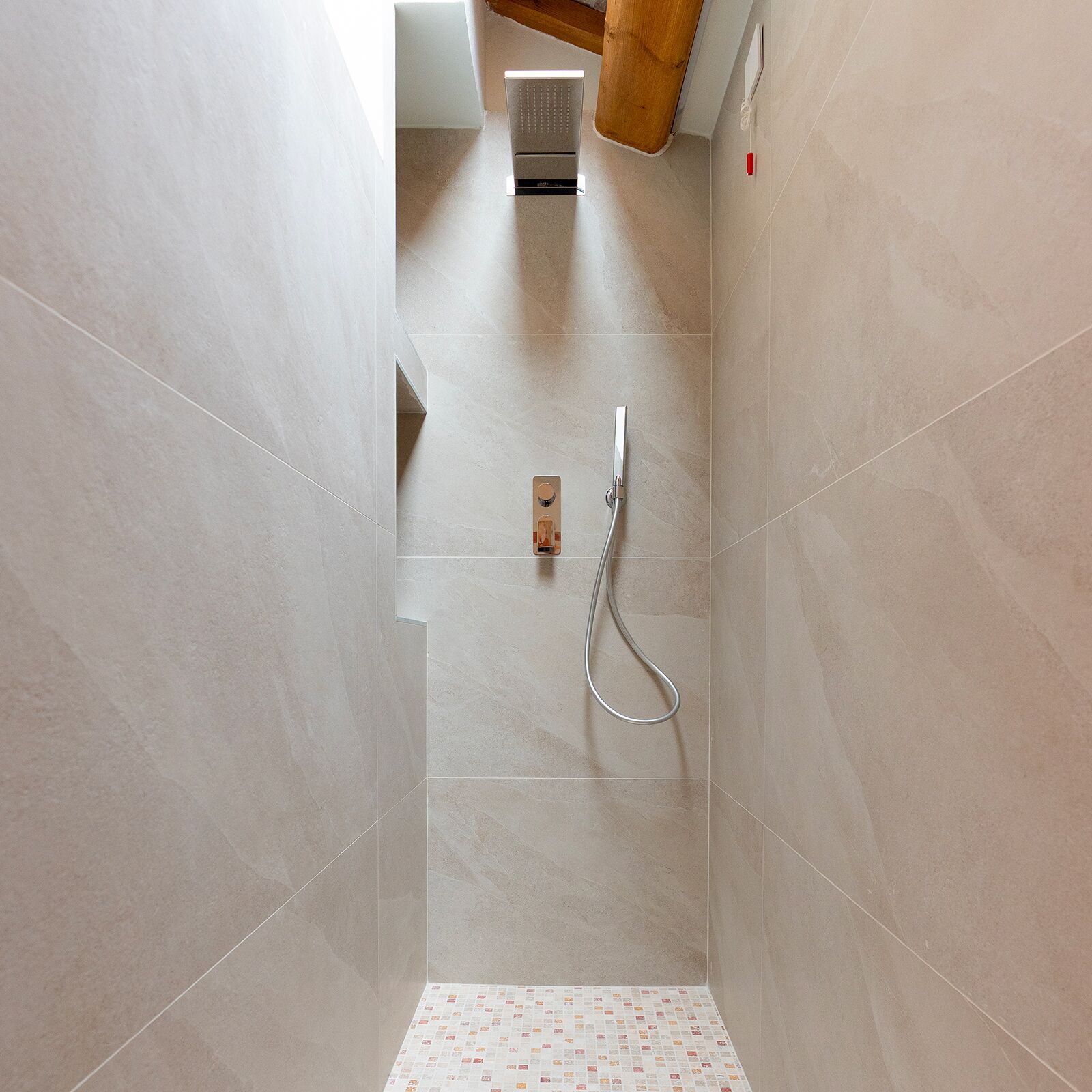Une douche moderne dotée d’un pommeau de douche à main et d’un panneau de commande fixé au mur.