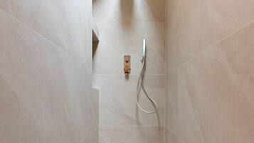 Une douche moderne dotée d’un pommeau de douche à main et d’un panneau de commande fixé au mur.