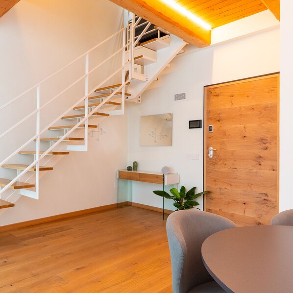 A modern interior with a wooden staircase, a dining area, and a wooden door. - Antica Corte Lugo (Lugo)