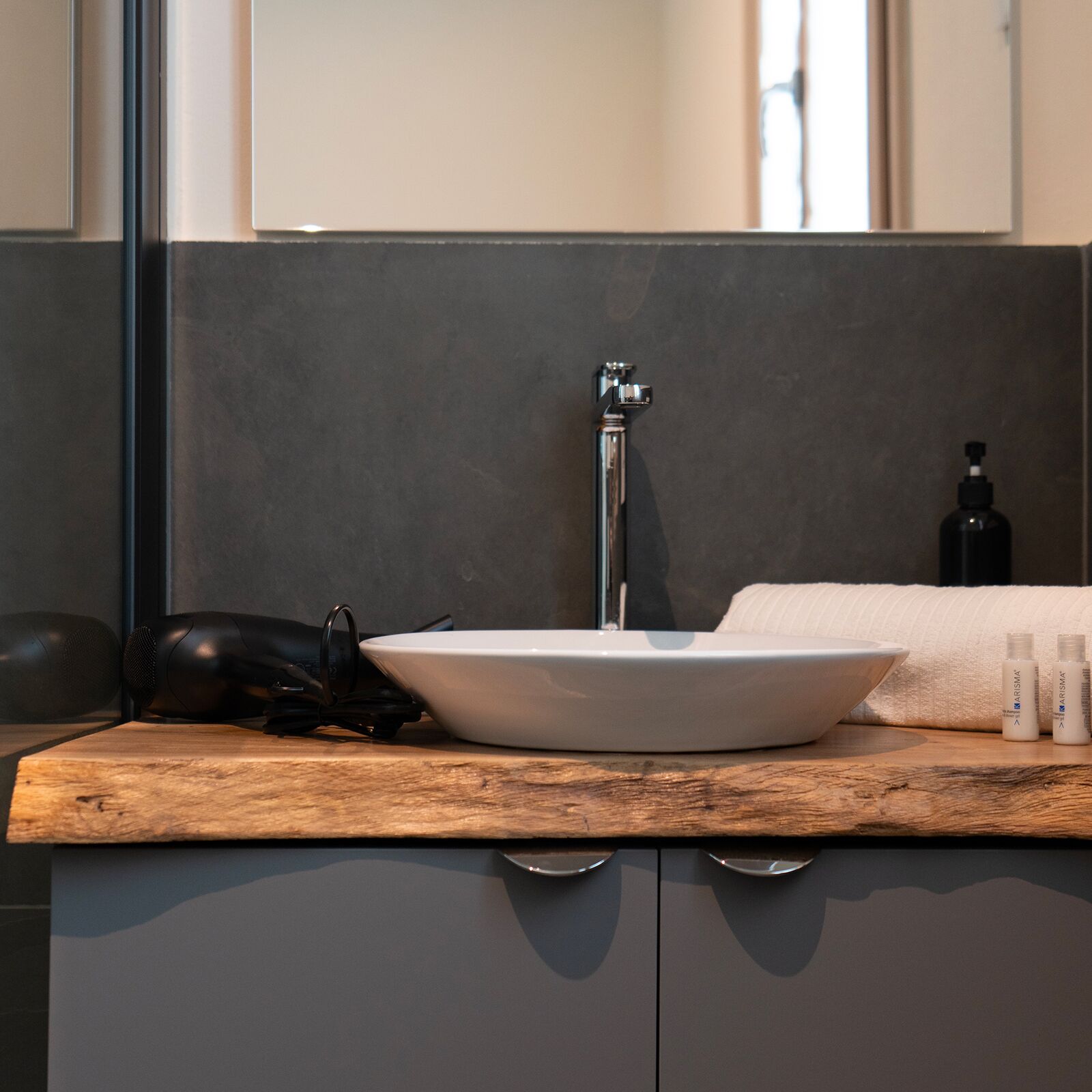 A modern bathroom with a white sink, a black telephone, and a towel on the counter.