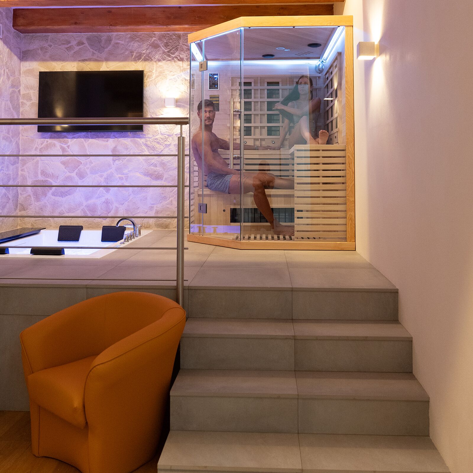 Een moderne badkamer met een glazen douchecabine, een houten trap en een flatscreen televisie aan de muur.