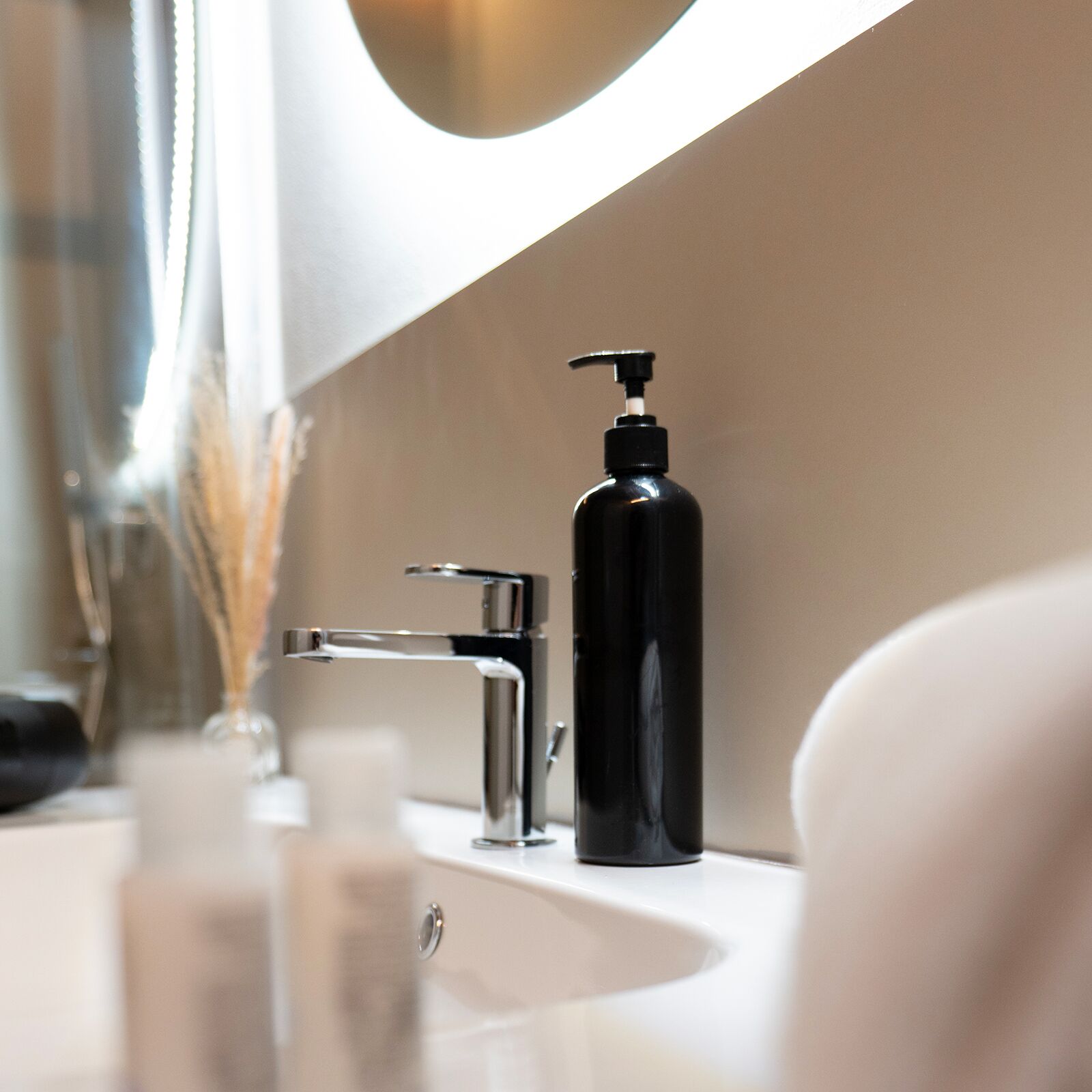 Une salle de bain moderne avec un robinet chromé, un distributeur de savon noir et un lavabo blanc.