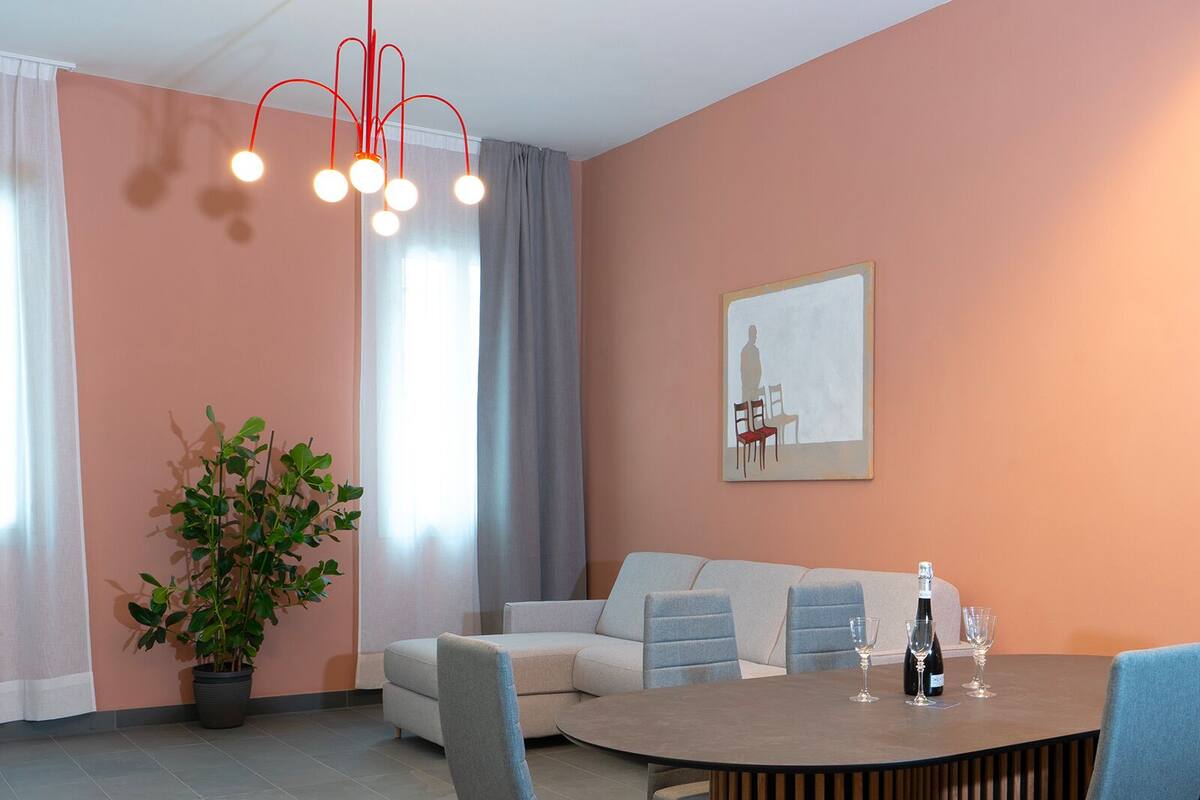 A modern living room with a round dining table, grey sofas, and a potted plant.