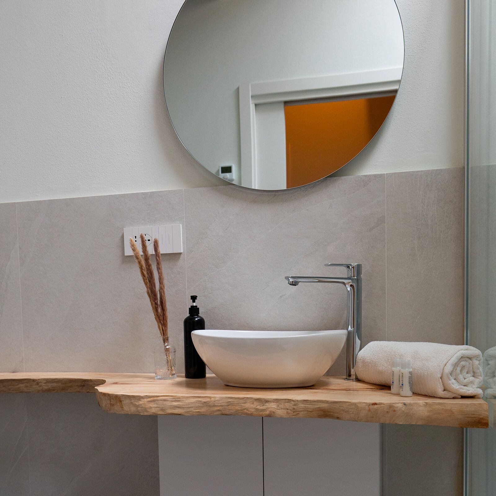 A bathroom with a round mirror, a white sink, and a towel.