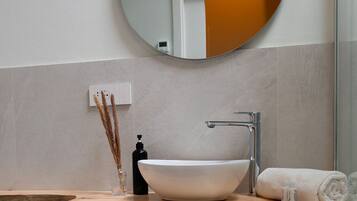 A bathroom with a round mirror, a white sink, and a towel.