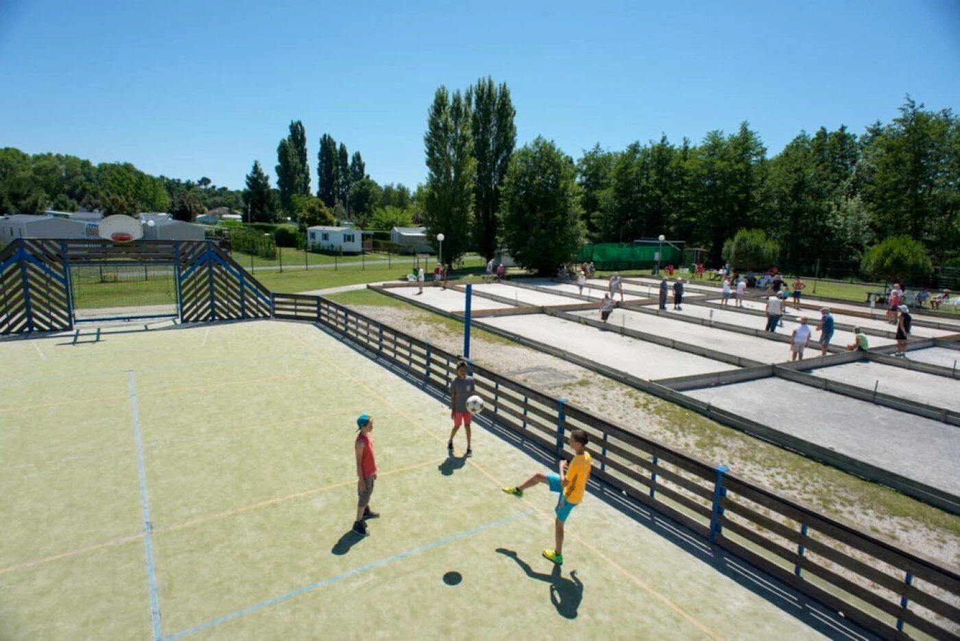 An outdoor sports court with a basketball hoop and a volleyball net.