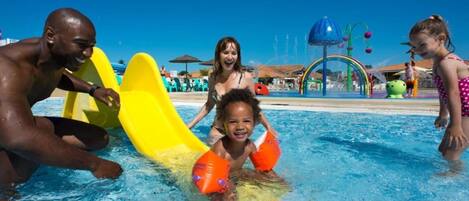 Una piscina con un tobogán amarillo y zona de juegos acuáticos.