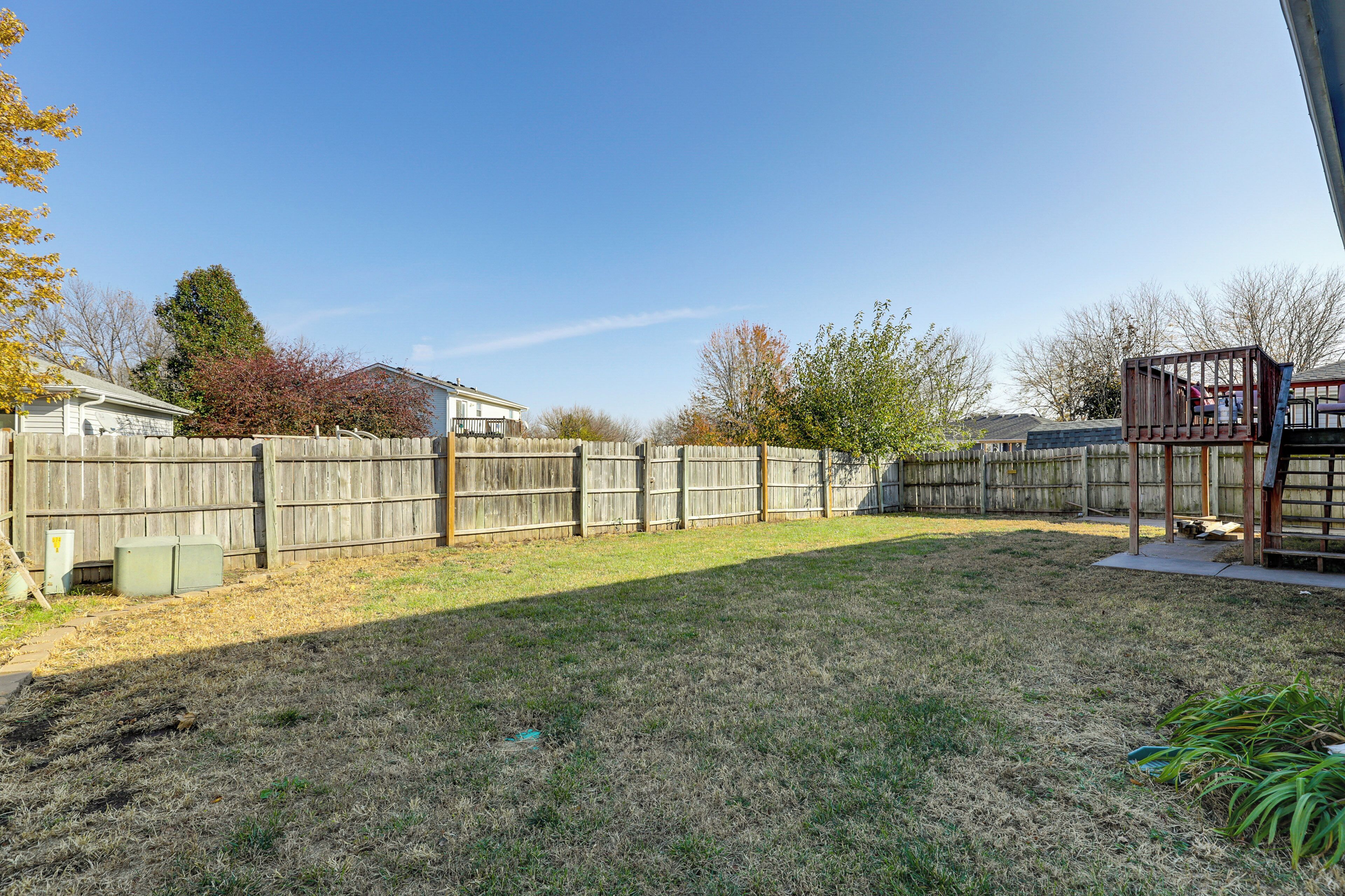 A backyard with a wooden fence, a patio area, and a small shed.