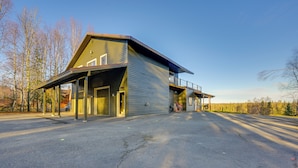 Ein modernes Gebäude mit flachem Dach und großen Fenstern, inklusive überdachter Außenbereiches und einer sichtbaren Garage.