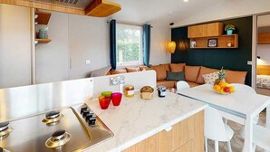 Une cuisine compacte équipée d’une cuisinière à gaz, d’une petite table à manger et d’un coin salon avec un canapé.