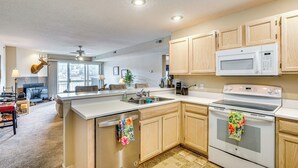 A modern kitchen with wooden cabinets, a built-in microwave, and a dishwasher. - Lakefront Osage Beach Condo w/ Water-View Balcony! (Osage Beach)