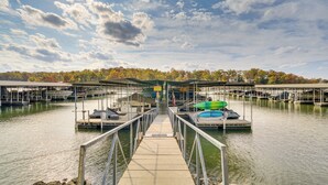 A pier leading to a marina with docks and boats. - Lakefront Osage Beach Condo w/ Water-View Balcony! (Osage Beach)