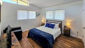 A bedroom with a bed, two bedside lamps, a TV, and a desk. - 2 Mi to Cocoa Riverfront Park: Home w/ Patio! (Cocoa)