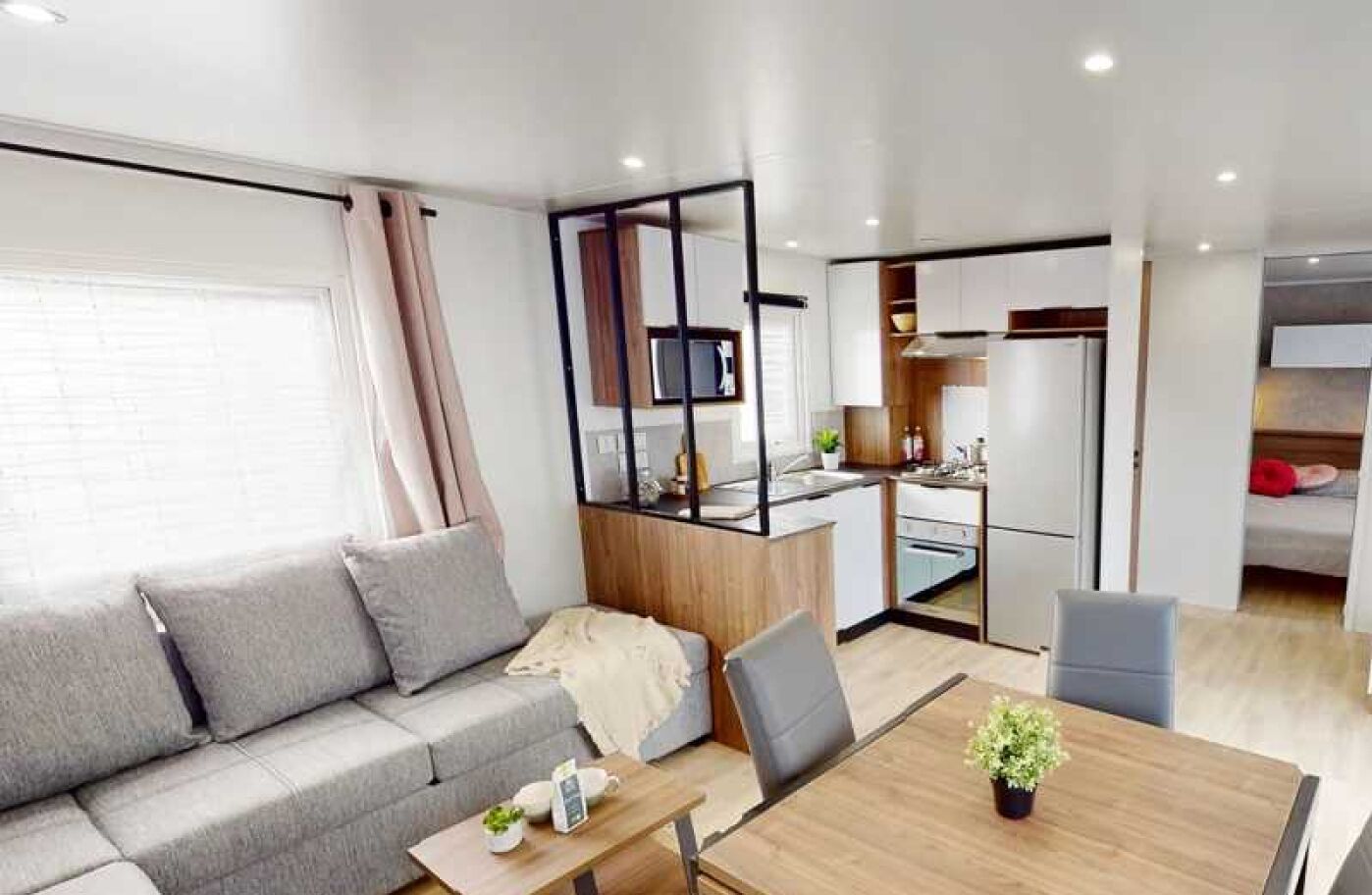 En moderne og kompakt opholdsstue med sofa, spisebord og tekøkken.
