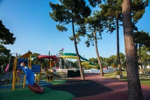 Explore the outdoor playground with slides and climbing frames set amidst lush surroundings.