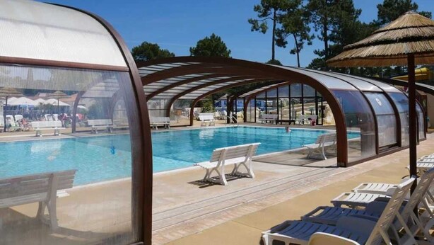 Ett poolområde med en överbyggd sittplats och solstolar.