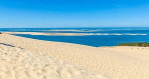 Paisagem desértica com dunas de areia e vista para o oceano.